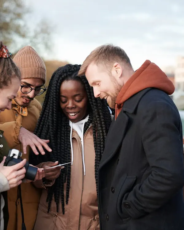 Four friends laughing over a phone together